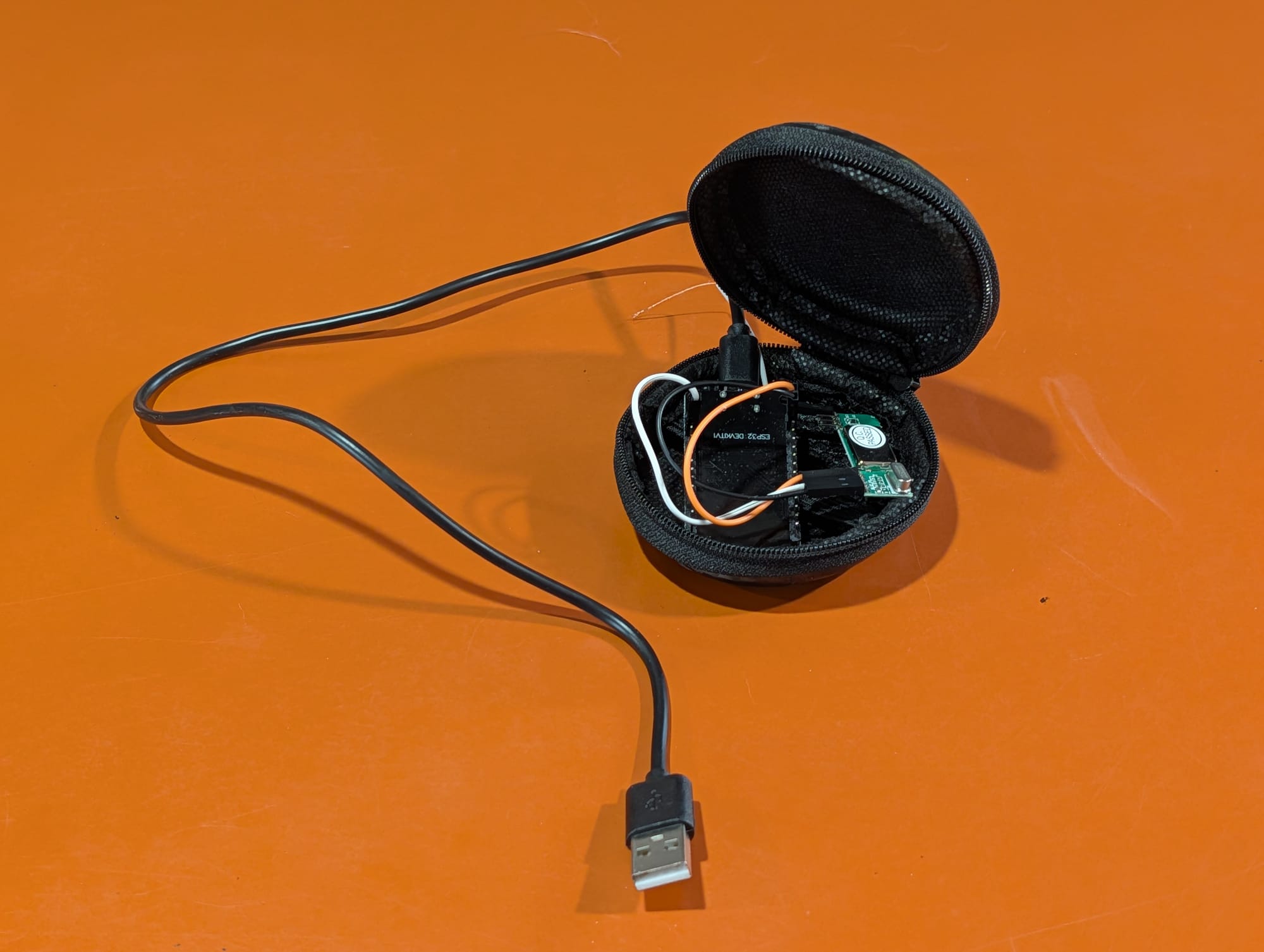 The same earbud case open, revealing the ESP32 dev board and receiver nestled inside